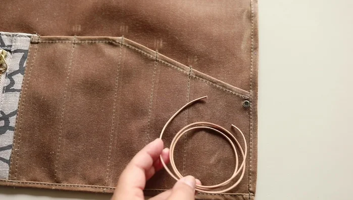 Load and finish: Load tools and roll the tool roll. Wrap and secure the leather cord.