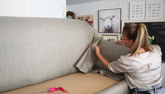 Attach the rolled arm piece. Stuff the bottom part, staple it, and make relief cuts where necessary to accommodate the sofa's structure. Ensure smooth fabric lay by adjusting relief cuts as needed.