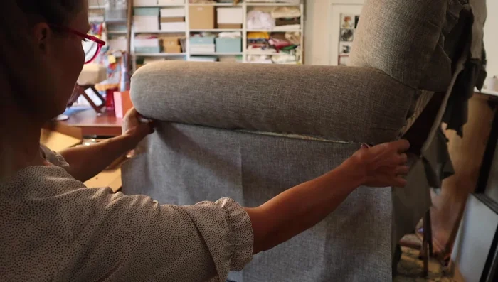 Secure the back using tack strip. Install a tack strip under the fabric to maintain a straight edge. Cover with Dacron for plumpness.