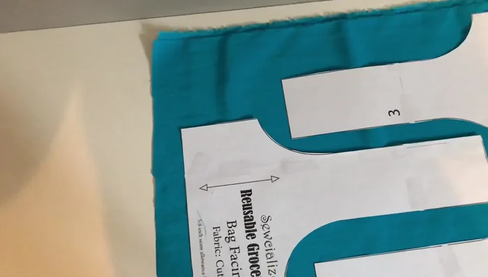 Measure and pin grain lines to ensure pattern pieces are parallel to the selvage and not overlapping. Pin the rest of the pattern pieces and cut them out.