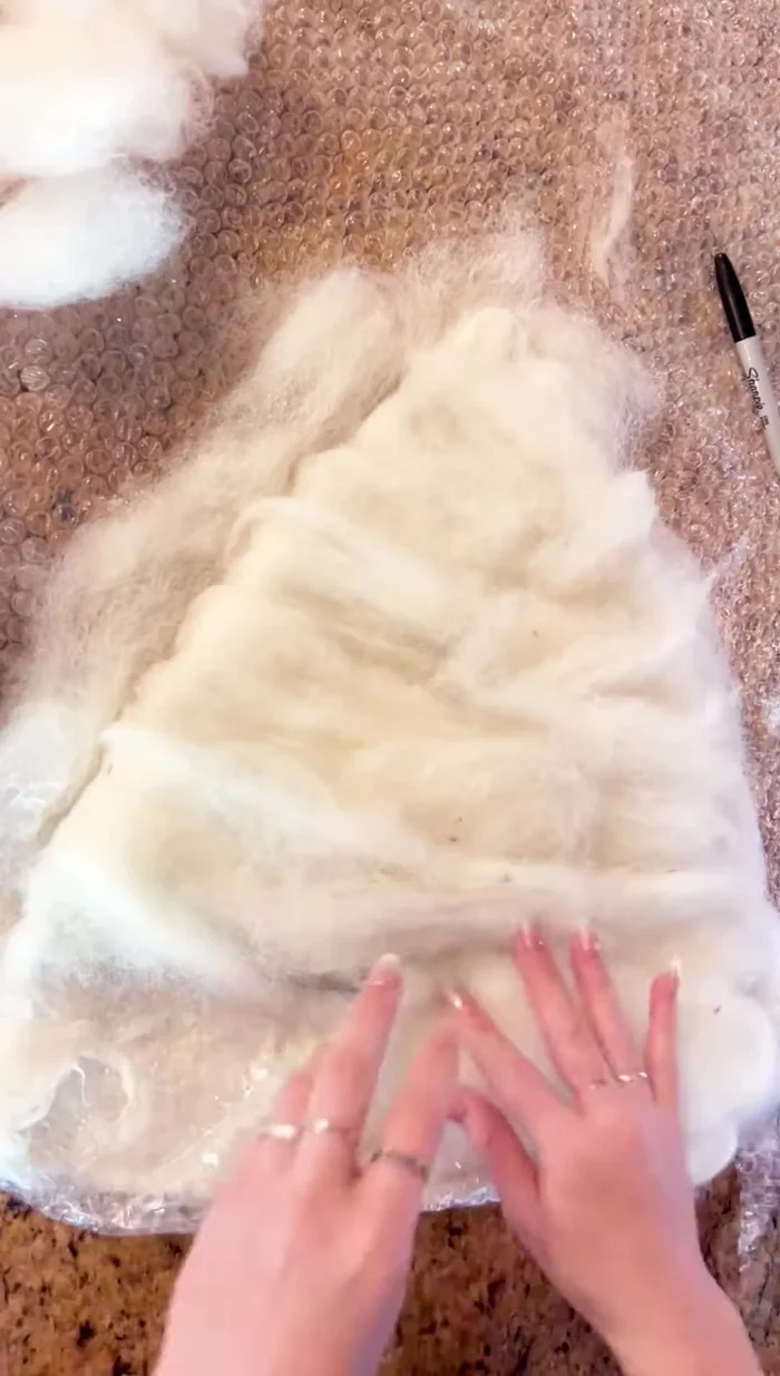 Create the second hat section by layering wool, spritzing, and pressing. Fold down the edges.