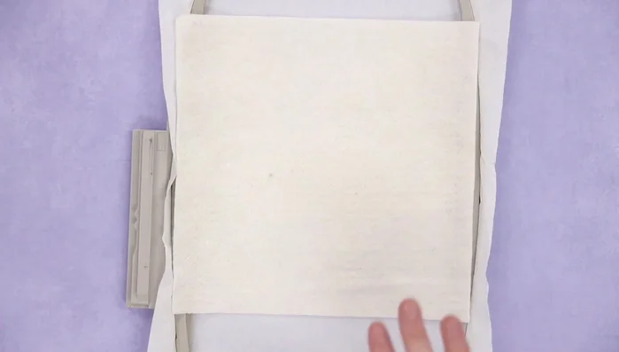 Place base fabric over the batting, leaving seam allowance, and secure with tape.