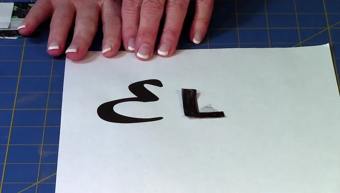 Apply letters: Remove paper backing from fusible web, place on fabric, and finger press. Cut out fabric letters along drawn lines.