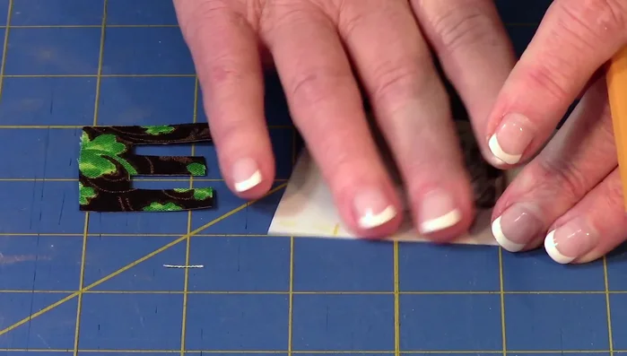 Apply letters: Remove paper backing from fusible web, place on fabric, and finger press. Cut out fabric letters along drawn lines.