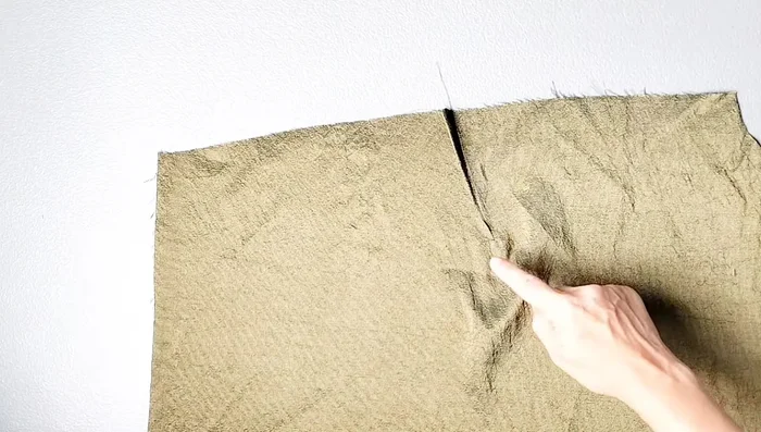 Sew basting stitches along the top of the lining sleeves. Sew the underarm seam of the right lining sleeve. Leave an opening between the notches on the left lining sleeve.