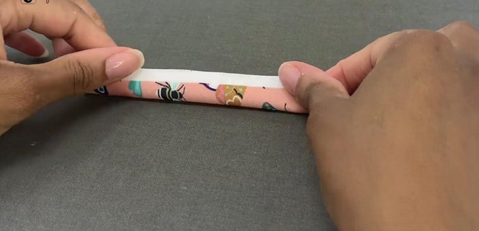 Prepare the hanging loop: Fold the small fabric piece in half, open, and fold again using the crease as a guide. Fold both edges towards the center and clip to hold.