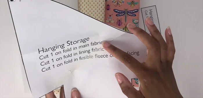 Prepare the hanging loop: Fold the small fabric piece in half, open, and fold again using the crease as a guide. Fold both edges towards the center and clip to hold.