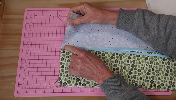 Fold the ribbon in half and stitch it to the top edge above the pocket. 