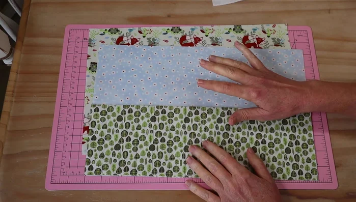 Cut three 36cm x 24cm rectangles from your chosen fabrics (one for the back, one for the inside lining, and one for the pocket). Cut a 34cm x 22cm rectangle of wadding.