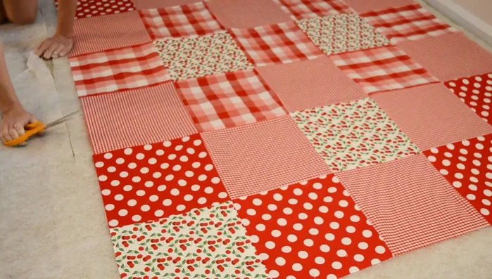 Cut quilt batting, leaving 2 inches extra around the perimeter. Cut tablecloth to the same dimensions.