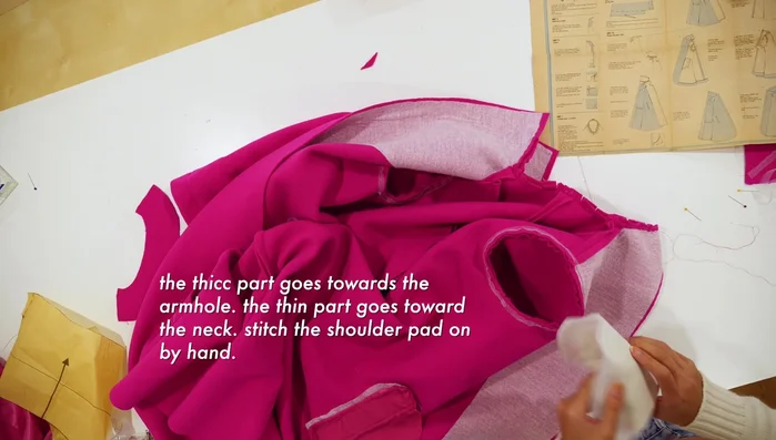 Hand-stitch shoulder pads, positioning the thick part towards the armhole and thin part towards the neck.