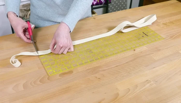 Attach webbing handles: Find center of outer fabric. Mark 3.5 inches on both sides. Pin webbing 1/8 inch from edge, starting from bottom. Sew, stopping at 1.5 inches from top. Repeat for other handle.