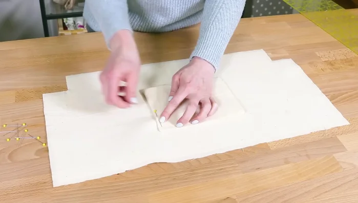 Attach pocket and zipper: Center pocket 3 inches from top of lower lining piece. Pin and sew. Place zipper face up on lower lining piece. Place upper lining piece on top, facing down. Align edges, sew. Repeat for other side.