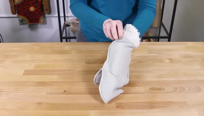 Place the faux fur lining inside the fleece mitten, ensuring a proper fit. Pin around the bottom with a ¼ inch seam allowance, leaving a 2-3 inch gap. Pull the lining through the gap and tuck it inside the fleece.