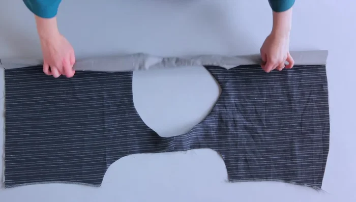 Lay your bodice flat with the main fabric facing upwards. Starting at one armhole, roll the entire bodice (main fabric and lining) towards the other armhole. Flip the lining under the rolled bodice to meet the main fabric bodice. Align the lining and main fabric armholes with right sides together.