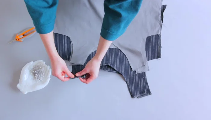 Match the main fabric and lining fabric together at the neckline with right sides together. Make sure your shoulder seams are aligned. Stitch around the neckline with a straight stitch. Trim and grade your seam allowances. Clip the curved areas (or snip into the center point for a V-neck).