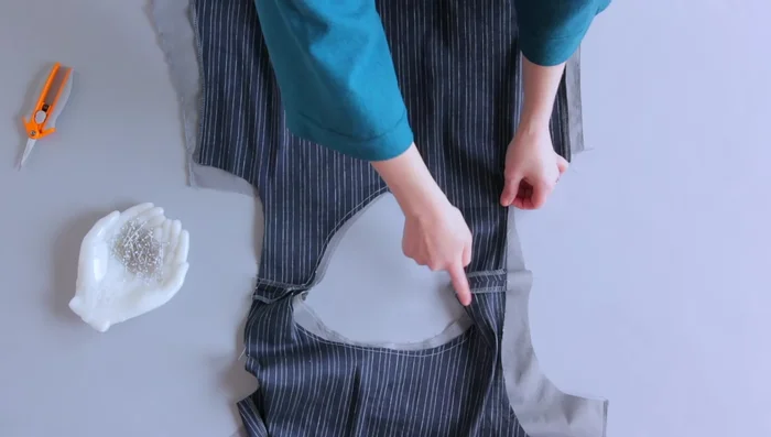 Match the main fabric and lining fabric together at the neckline with right sides together. Make sure your shoulder seams are aligned. Stitch around the neckline with a straight stitch. Trim and grade your seam allowances. Clip the curved areas (or snip into the center point for a V-neck).