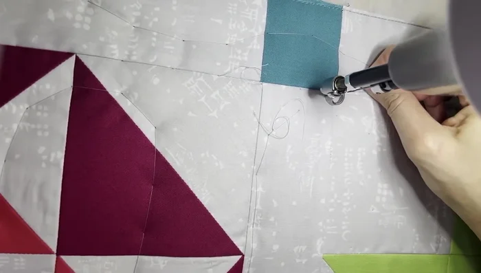 Outline the block: Stitch in the ditch along the seams of the maple leaf block, using a long arm quilting ruler as a guide. Pay attention to keeping stitches centered in the seam.