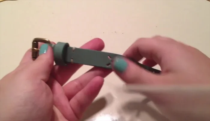 Measure and cut two pieces of belt: one from the buckle about two inches from the belt loop; the second, from the back, about one inch and cut it off.