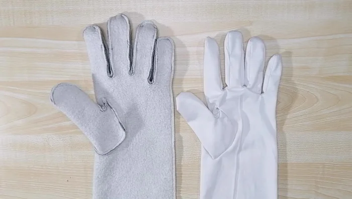 Insert lining. Turn the glove wrong side out and the lining right side out. Insert the lining into the glove, ensuring thumbs align. Remove your hand and sew the hem allowances of the glove and lining together. 