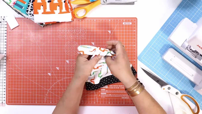 Tie the hat: Cross over the two top points of the hat and tie them in a knot to create the hat's shape.