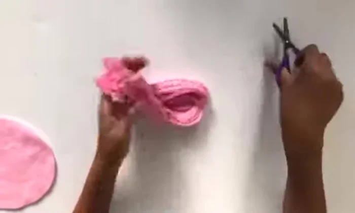 Sew the yarn onto the pink piece using the three pre-punched holes on each side. Knot the yarn after securing it.