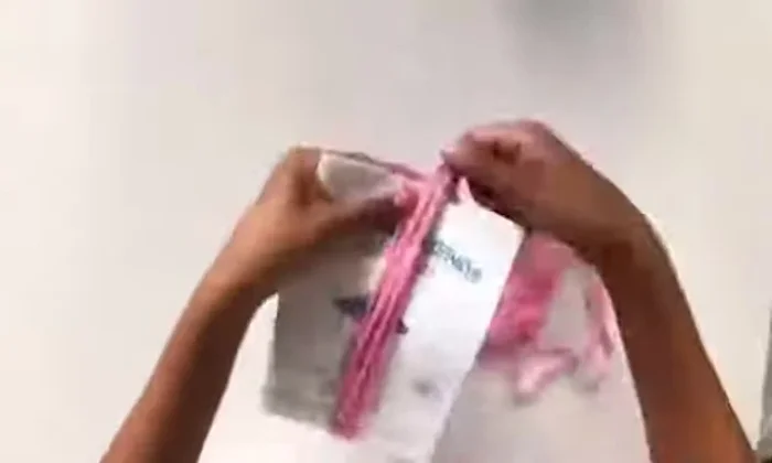 Wind pink yarn around the instruction book 15 times, slide it off, and tie the top with pink thread. Cut the other side.