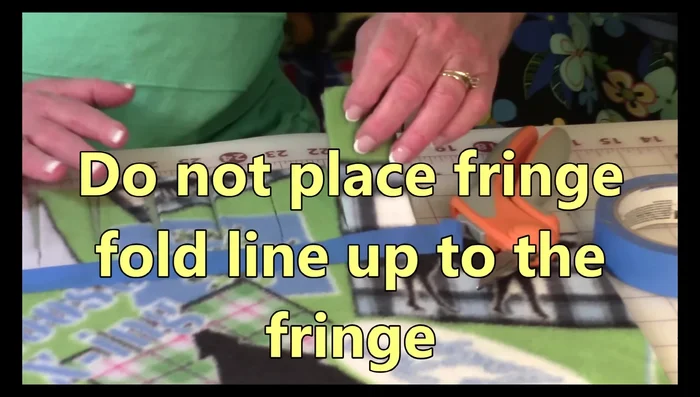 Grab both layers of fringe and fold them towards the tape, about half an inch from the tape. Snip the fringe close to the fold.