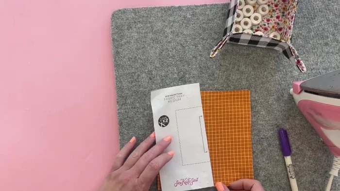 Use the template to mark the bottom corners of the tray. Adjust the template by 1/4 inch on three sides to account for seam allowance. Mark points 1.5 inches from each corner on the dotted line that will form the tray's bottom.