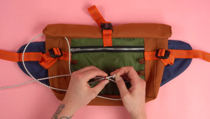 Feed the elastic cord through the bottom loops and back through the loop on the opposite side, repeating until all rings are used.