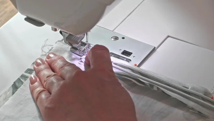 Sew the first side of the invisible zipper to the fabric, removing pins as you go. Keep the needle to the left for easier sewing.