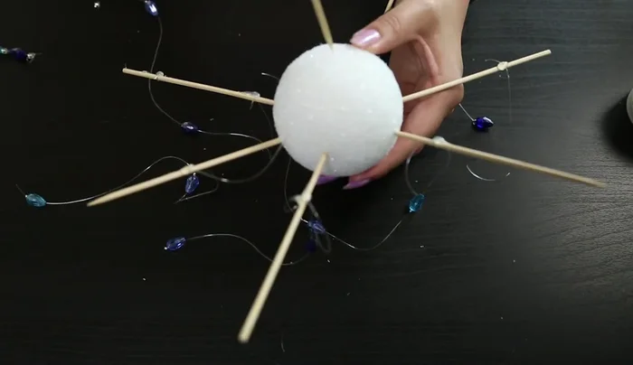 Create a hole at the top of the Styrofoam ball (ideally beforehand) to insert a longer string for hanging.