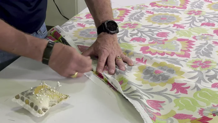 Match patterns and pin: Start at the center of both fabric panels, matching patterns to the selvage edge. Fold the top fabric back slightly, matching the pattern. Pin horizontally along the edge, ensuring the pins are perpendicular to the edge.