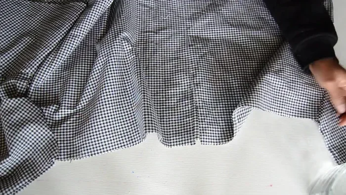 Gather the neckline by creating a 1-inch tunnel around the top edge, inserting a leather string using a safety pin, and tightening to desired fit.