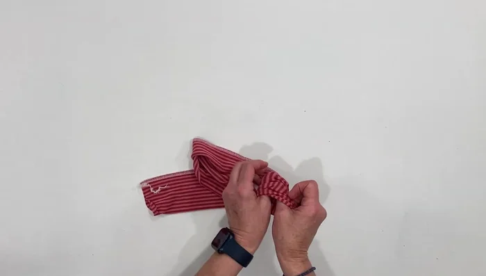 Bring the seam to the center, cross it over, and make a loose knot.