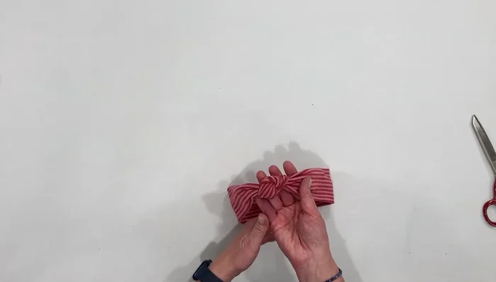 Bring the knot over the top of the seam and hide it.