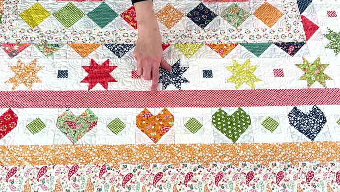 Add the first print border (red gingham) with small easy corner blocks at the corners.