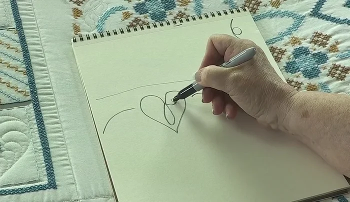 In areas around embroidered elements, create a delicate design that complements the embroidery without stitching directly on it. The example uses teardrops and small feathers.