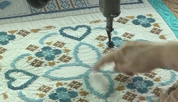 For the central area, use a larger pattern (e.g., feathers) that adds visual interest without overwhelming the cross-stitch.