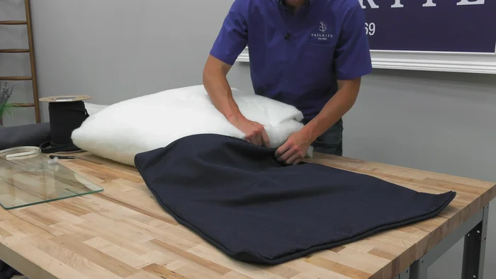 Carefully stuff the pillow cover with the prepared filling. Start by stuffing the bottom edge of the polyester batting into the cover, then add the rest.