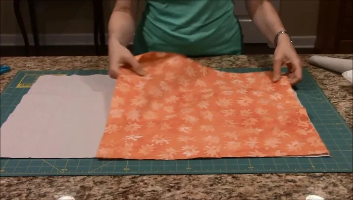 Fold the backing fabric in half lengthwise and cut it in half, creating two pieces.