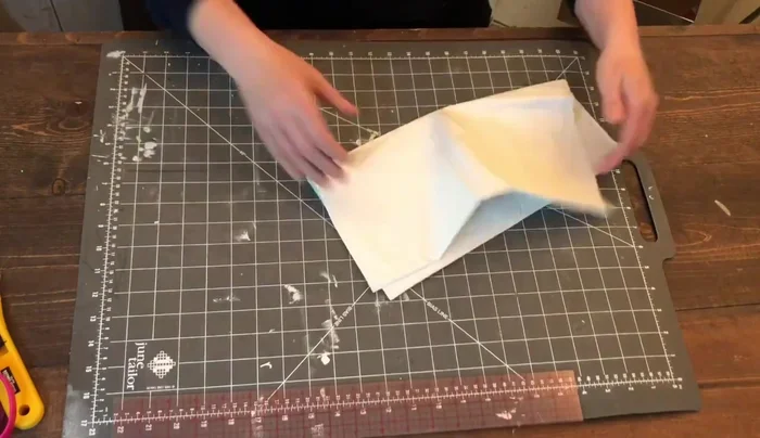 Cut the single folded edge at the bottom to create two separate pieces.