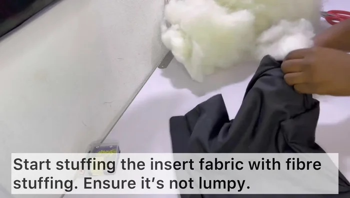 Stuff the insert with fiber, ensuring even distribution and filling corners. Avoid overstuffing. Top stitch the tab closed.