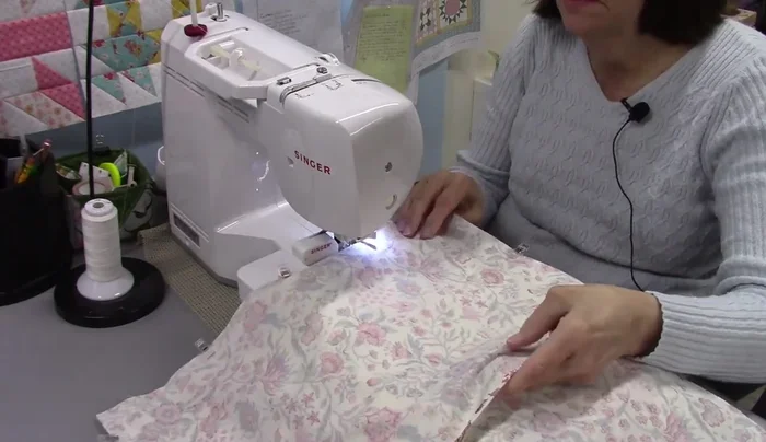 Cut and sew the backing: Cut two pieces of fabric for the back, 18 inches long by about 12 ¾ inches wide. Create a ¼ inch double fold hem on each piece. Sew the pieces together, leaving a 6-inch gap for turning.
