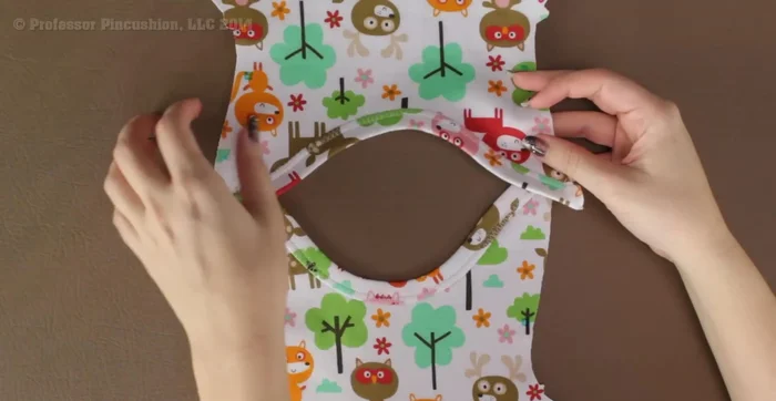 Assemble the onesie: Place the front and back pieces right sides together, matching the neckline and shoulder seams (indicated by square marks on the pattern). Pin and baste stitch to hold.