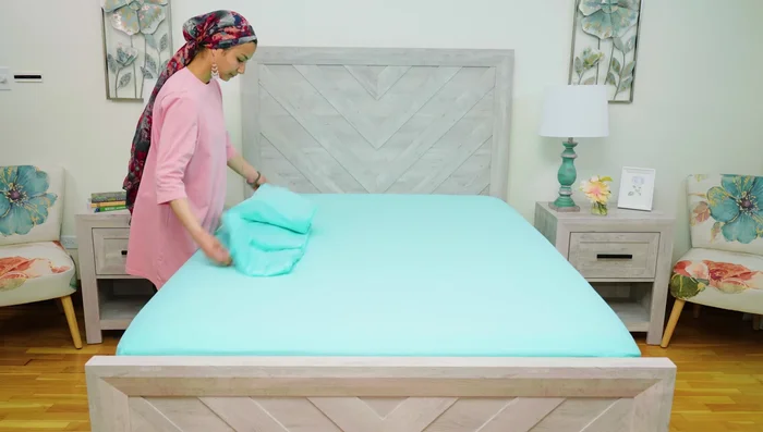 Tuck the flat sheet under the mattress, smoothing it out and creating box corners.