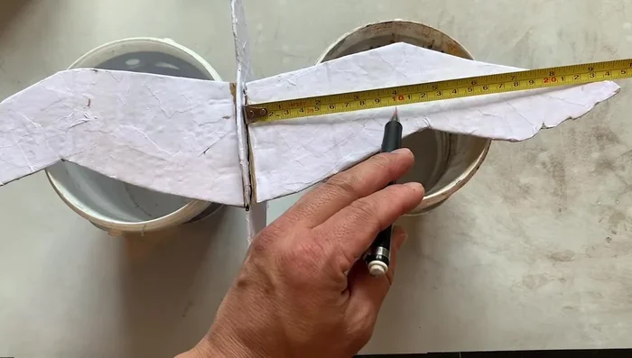 Prepare strings (one loop for hanging, two for wings, and one for the body). Attach strings to the holes, adjusting length for balance.