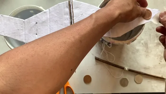 Hang the bird and adjust string lengths and coin placement to achieve balance. This may require several attempts.