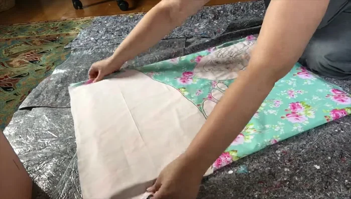 Attach the fabric-covered design to the wooden board using screws.