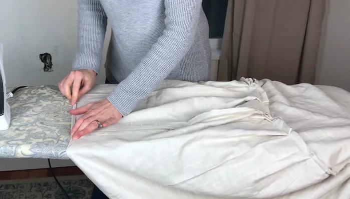 Open up the side hems of the ruffle for a flatter look, fold up the desired hem width, iron, and sew with a wide, loose stitch.